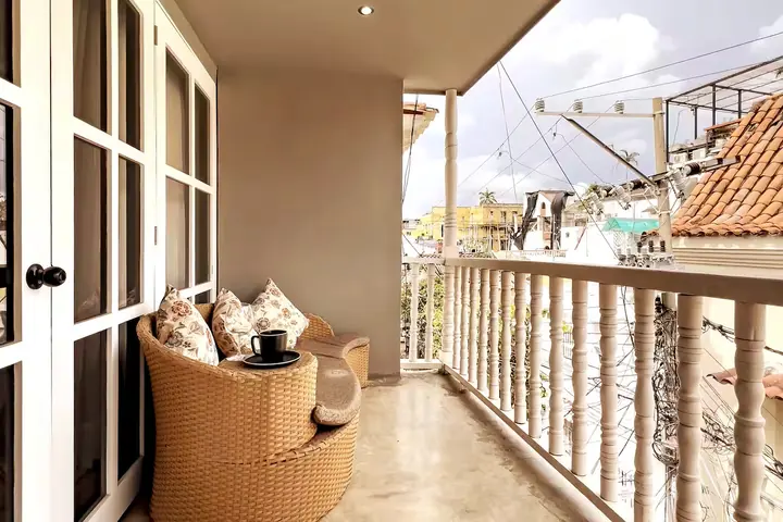 Street-side balcony with a rattan armchair and white balustrade