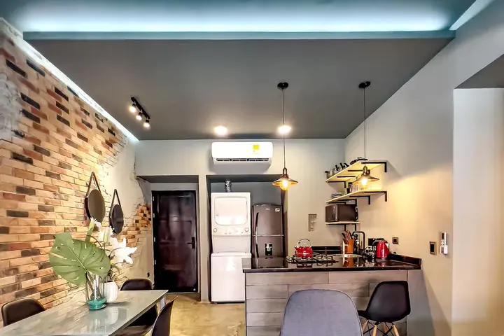 Open-plan kitchen with island, fridge and stacked washer and dryer