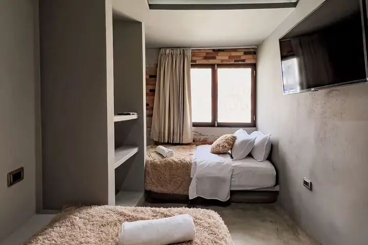 Bedroom with two single beds, built-in shelves and a wall-mounted TV