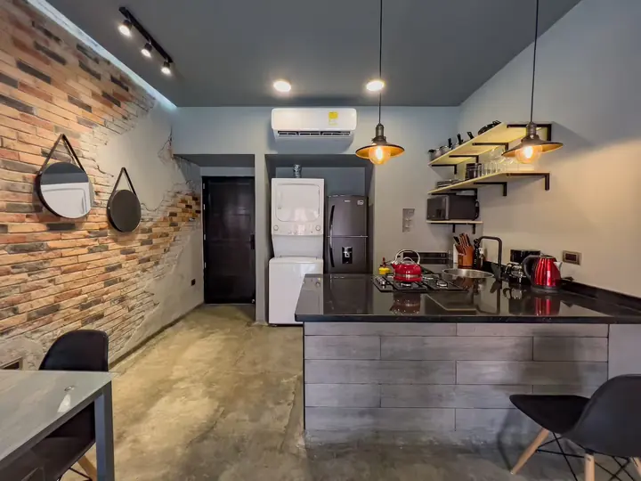 Kitchen seen from the dining area, with brick wall and round mirrors
