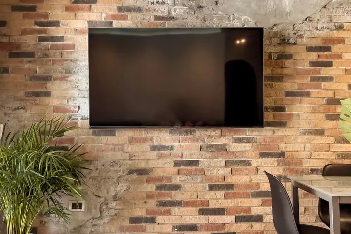Large TV mounted on the brick wall of the living room