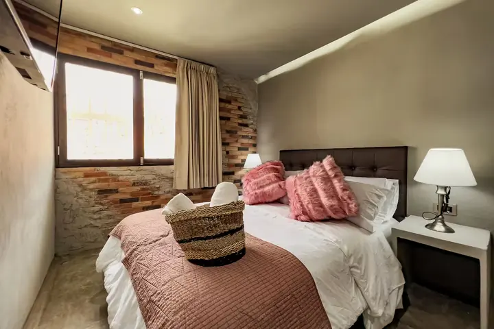 Queen bedroom with a window, curtains and brick detail
