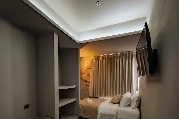 Twin bedroom with wall-mounted TV and curtains