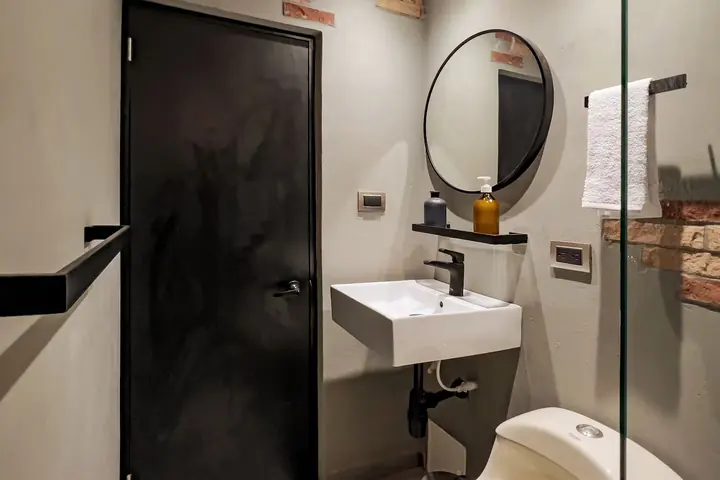 Bathroom with a wall-hung basin, round mirror and black fittings