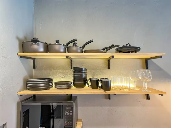 Shelves with pots, pans, plates, mugs and wine glasses