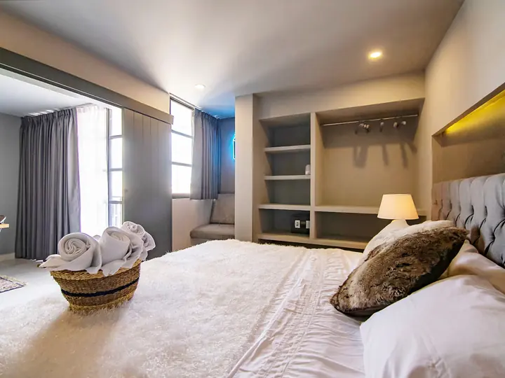 Bedroom with a large bed, grey upholstered headboard and built-in shelves