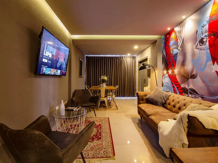 Living room with wall-mounted TV, armchairs and a patterned rug