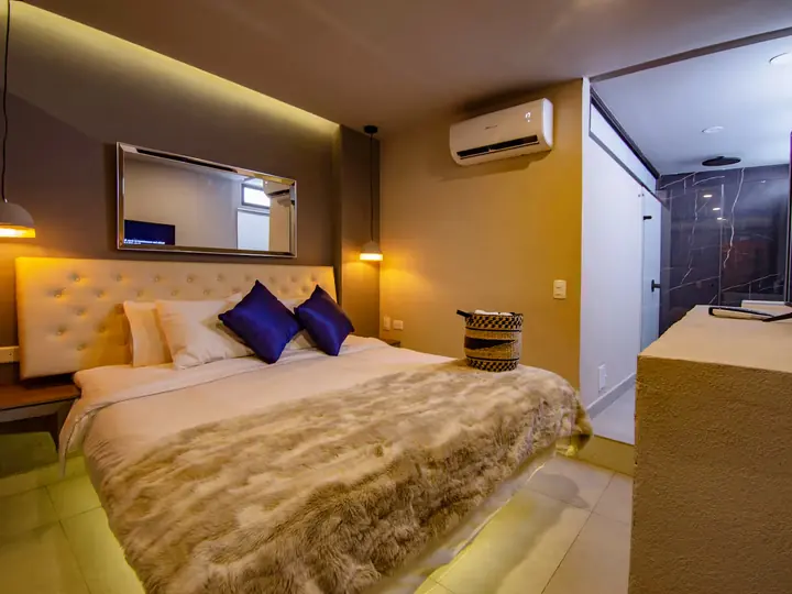 Bedroom with a queen bed, blue cushions and private bathroom