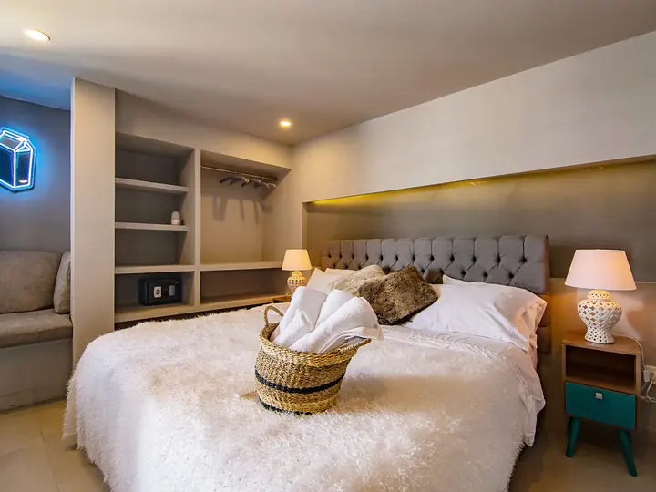 Bedroom with a white bedspread, towels in a basket and bedside lamps