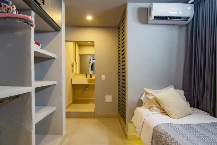 Single bed with built-in shelves and a private bathroom beyond