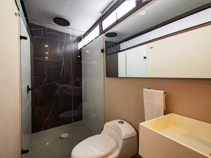Bathroom with dark marble-effect shower, toilet and basin