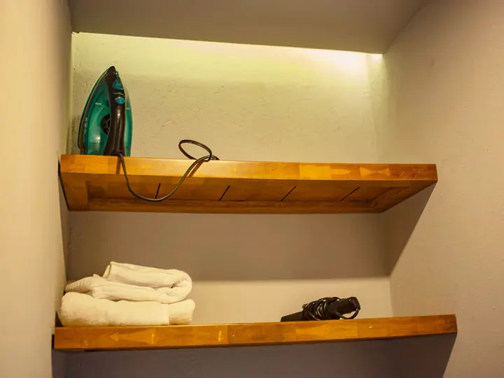 Iron and spare towels on wooden shelves